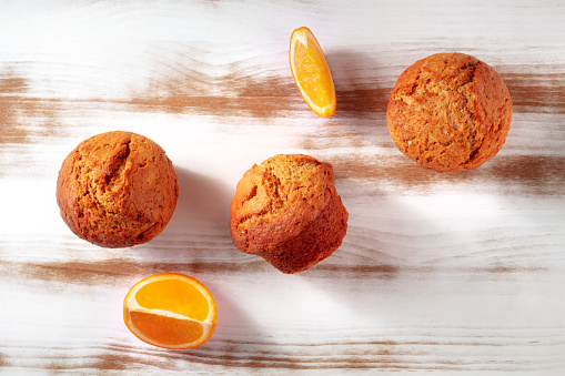 Orange muffins on a rustic wooden kitchen table, easy baking, overhead flat lay shot with copy space