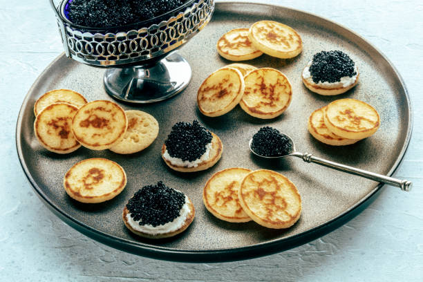 istock Blinis with black caviar and cream cheese, on a festive dish, mini pancakes 1751859666