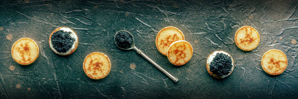 istock Blinis with black caviar and cream cheese panorama on a black slate background 1751859686