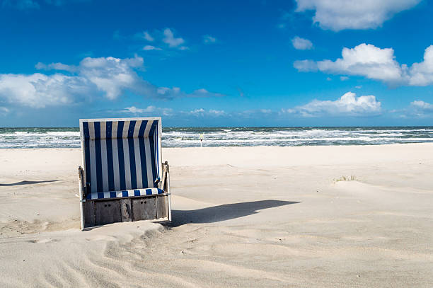 Hooded Beach Chair Empty hooded beach chair at the the coastline of the island Sylt - Germany. Copy space on the blue sky in the background. hooded beach chair stock pictures, royalty-free photos & images