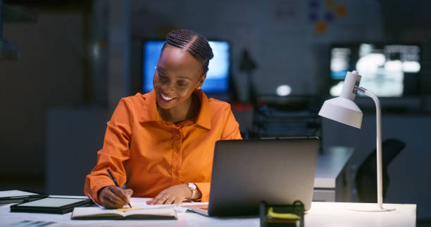 istock Business woman, writing notes and night research, data analytics planning or financial goals, results or target. Professional African person with notebook and laptop ideas, proposal or online report 1751859737