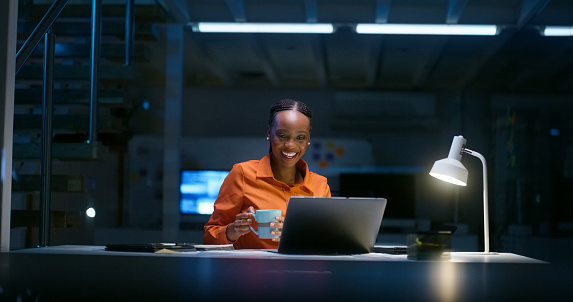 Night, office and black woman with video call on laptop for networking communication, contact and online chat. Dark, workplace and employee talking in virtual conference, webinar or b2b discussion