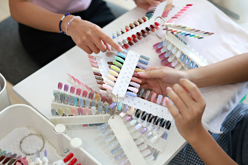 Young female business owner assisting customer in nail salon, high angle view