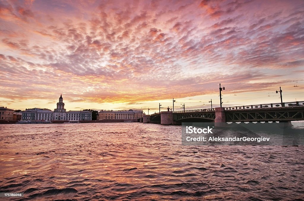 Sunrise View of Palace Bridge St Petersburg, Russia "Beautiful and dramatic sunrise view of Palace Bridge in St. Petersburg. Visible are University embankment on Vasilevsky Island, Neva river,  Rostral Columns, and fantastic sunrise cloudscape over the reflection in the water. Photo taken during white nights in St. Petersburg, Russia.See more images like this in:" St. Petersburg - Russia Stock Photo
