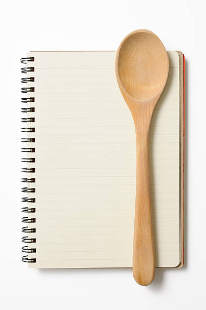 Blank spiral notebook with wooden spoon on white background