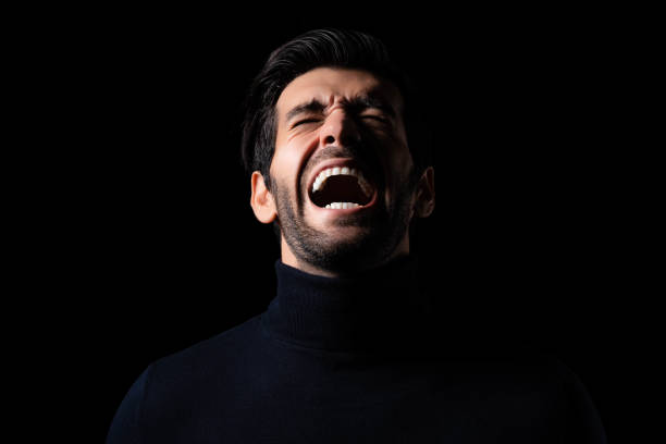istock Stressed Young angry man screaming and shouting Frustrated handsome man agonizing and torturing expression He get maddening and overwhelming rage in the dark room black background Agressive man 1751871422