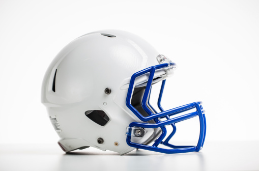 Football Helmet. A red football helmet sitting on artificial turf next to a yard line with a white background