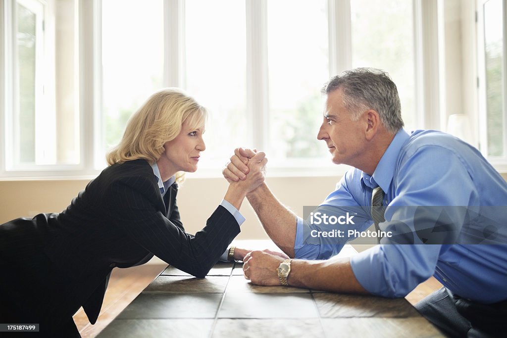 Businessman And Businesswoman Arm Wrestling Side view of mature businessman and businesswoman arm wrestling on tablehttp://i449.photobucket.com/albums/qq220/iphotoinc/MenBanner1.jpg 40-44 Years Stock Photo