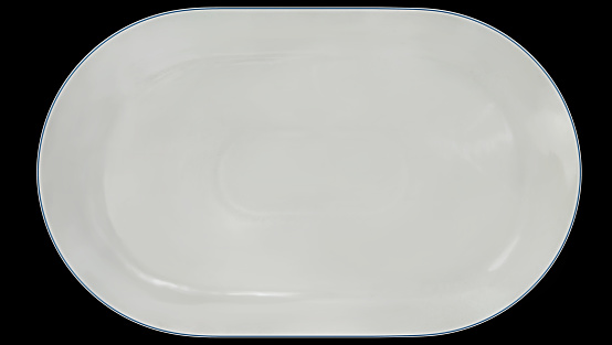 Blue rimmed white oval empty porcelain tray, isolated on black background, high resolution stock image.