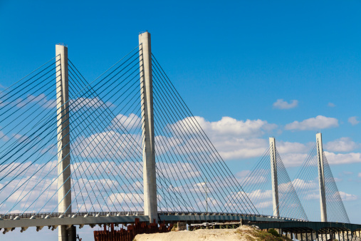 A cable-stayed pre-cast concrete bridge  crossing the Indian River Inlet in Delaware is nearing completion.  Beautiful cloud-filled blue sky serves a a nice backdrop to the bridge.