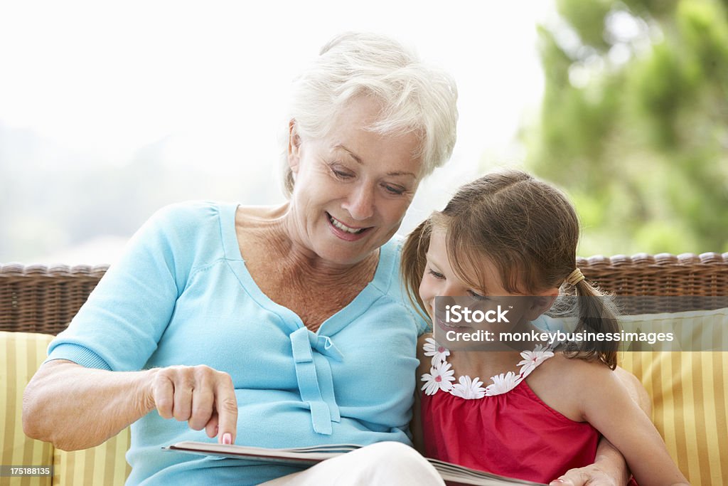 Grand-mère et petite-fille lire livre sur le jardin siège - Photo de Enfant libre de droits