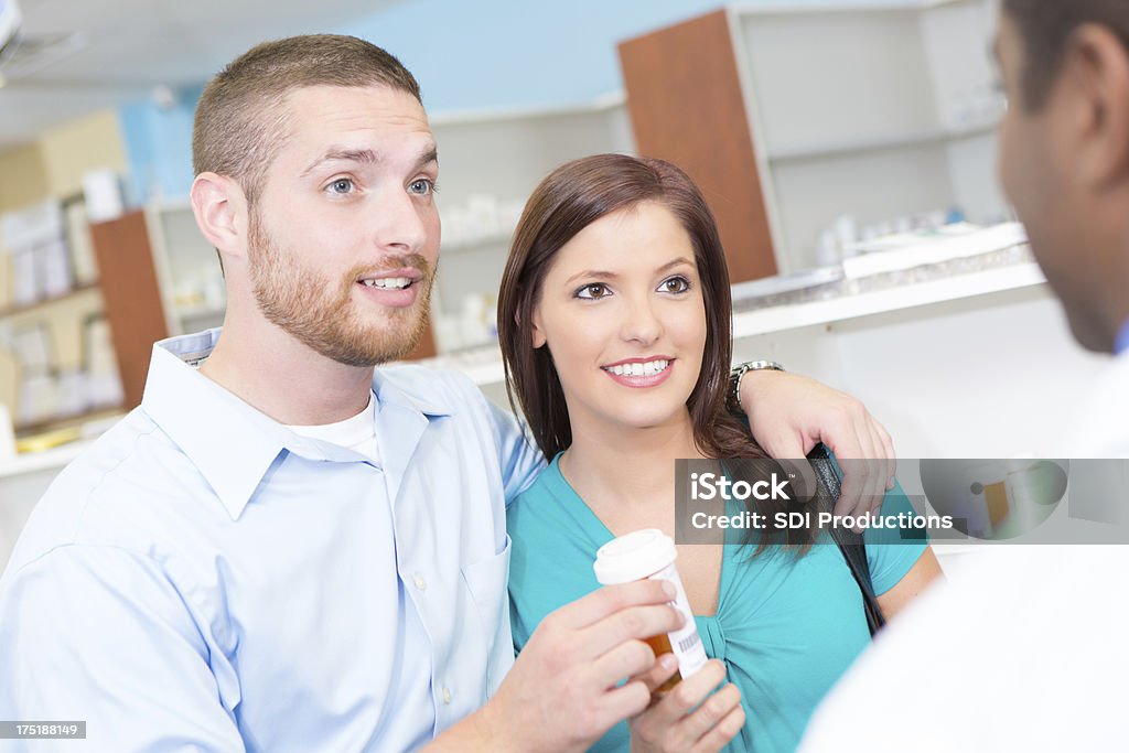 Marido e esposa na farmácia farmácia medicamentos com receita médica a falar de - Foto de stock de Adulto royalty-free