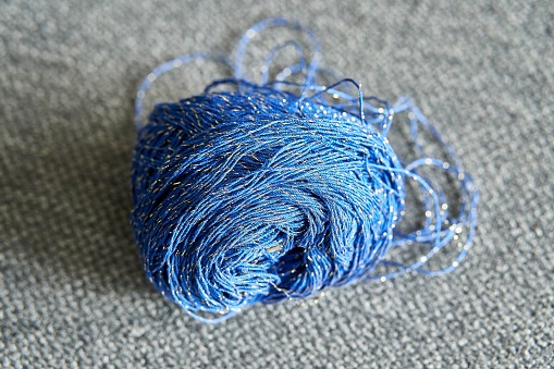 A blue woolen ball of yarn lying on a gray background