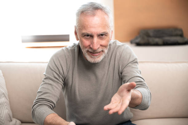 istock mature man sitting on sofa and talking by video call 1751885047