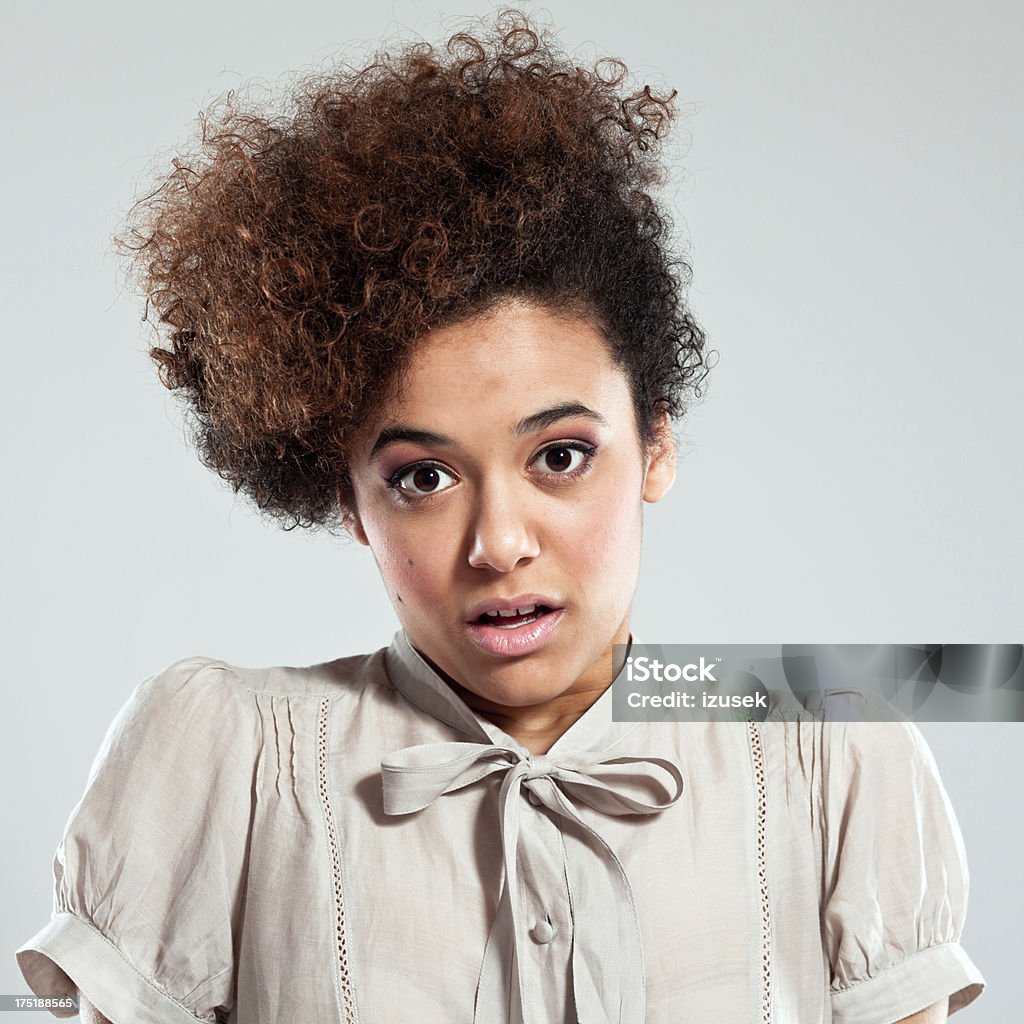 Shock Portrait of shocked teenaged afro girl looking at the camera . Studio shot, grey background. Rolling Eyes Stock Photo