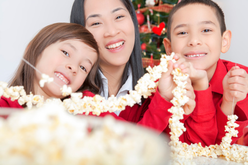 Happy asian family stringing popcorn