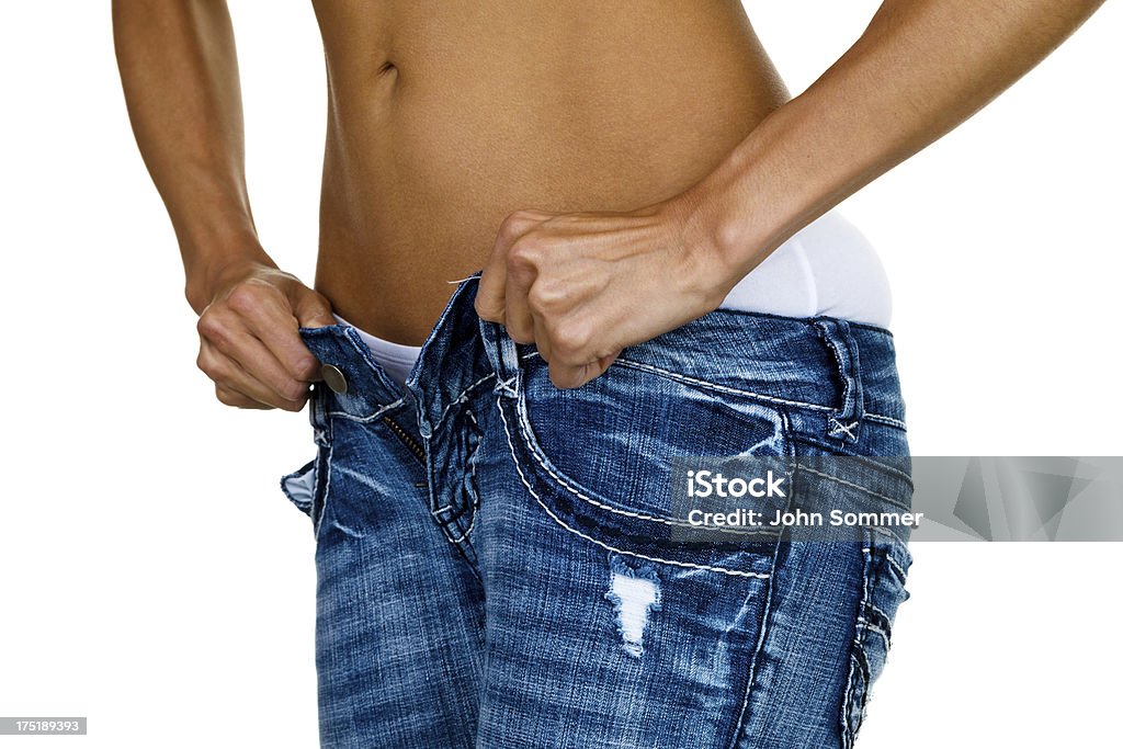 Woman trying to button tight jeans Closeup of a woman trying to button jeans that are too small for her body type  Pants Stock Photo