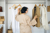 Young woman standing near wardrobe and select outfit for work