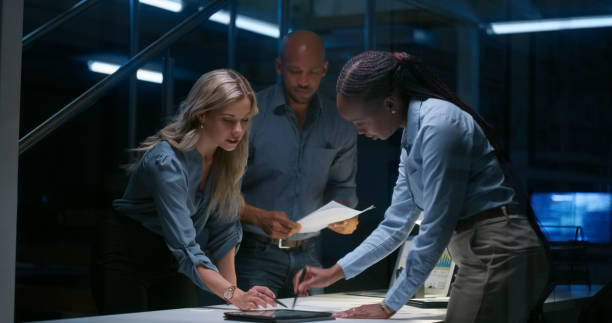 istock Business people, writing and planning at night in teamwork for strategy, ideas or brainstorming at office. Group of employees working late on team project plan, deadline or documents at workplace 1751900825