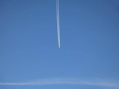 Airplane trail in the blue sky with white clouds and contrail.Vapor trail in the blue sky with white clouds on a sunny day