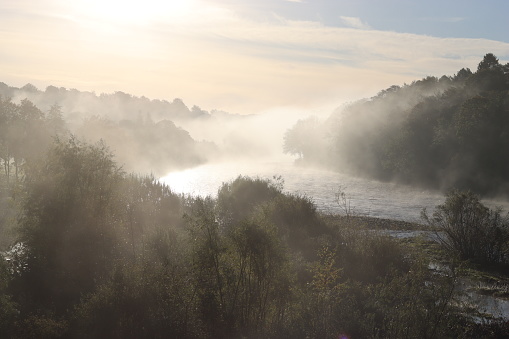 Mist rising over a countryside river in morning sunlight