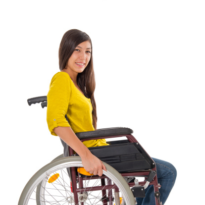 Disabled younf woman sitting in wheelchair. White background, studio shot