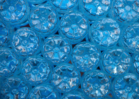 The bottom of empty mineral water bottles covered with drops. Focus is only on one.