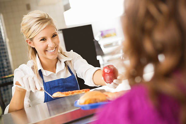Cafeteria serving healthy options to students Cafeteria worker offering healthy lunch options to middle school student cafeteria worker photos stock pictures, royalty-free photos & images