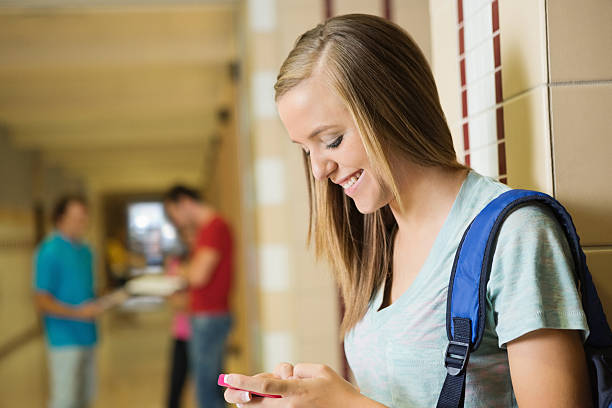 istock High school girl texting on her smart phone in hallway 175192695