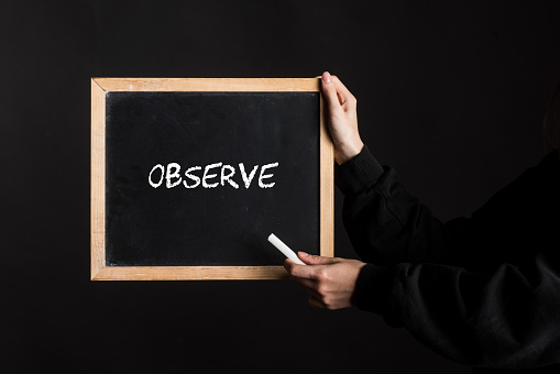 a blackboard sign with the word Observe written on it