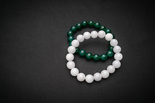 Top view of white and green jade rings on a black background. Close-up photo