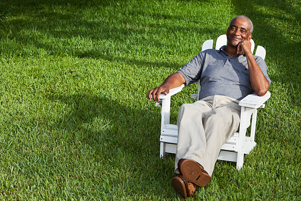 senior afrikanischen amerikanischen mann sitzt im adirondack-stuhl - sc0569 stock-fotos und bilder