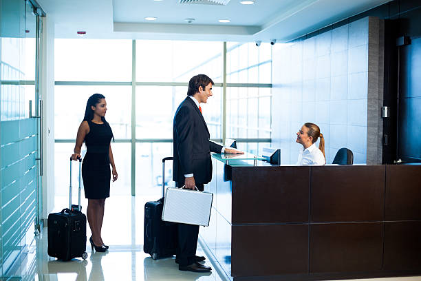 The receptionist and a client disucuss at the hostel reception desk.