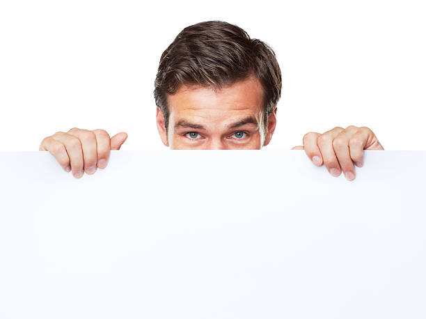 I'm holding this here for you - Copyspace A happy mature man holding up a blank board and covering his face - Isolated peeking stock pictures, royalty-free photos & images