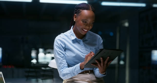 istock Woman, tablet or night office for deadline project manager, plan or online communication. African person, smile or dark internet work proposal or info search email or company growth, reading or idea 1751962941