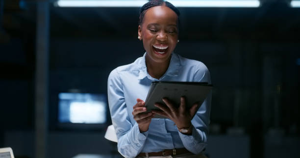 istock Tablet, night and a business black woman laughing in her workplace while working late on research. Technology, smile or funny with a happy young employee for work at a dark office in the evening 1751963058