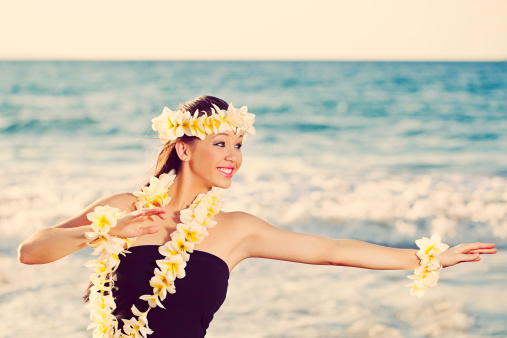 Young Hula Dancer posing for the camera seaside wearing a lei and haku headpiece.