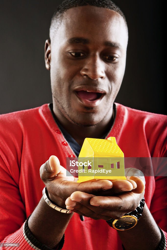 Amazed man looks down a yellow toy house 20-29 Years Stock Photo