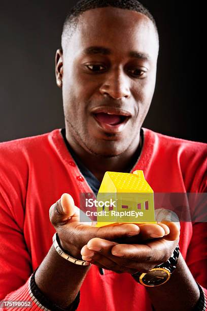 Amazed Man Looks Down A Yellow Toy House Stock Photo - Download Image Now - 20-29 Years, 30-39 Years, Adult