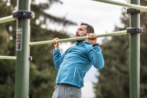 istock Young man working out calisthenics in an outdoor gym using parallel bars. He does push-ups on the bar. Concept of healthy lifestyle. 1751983591