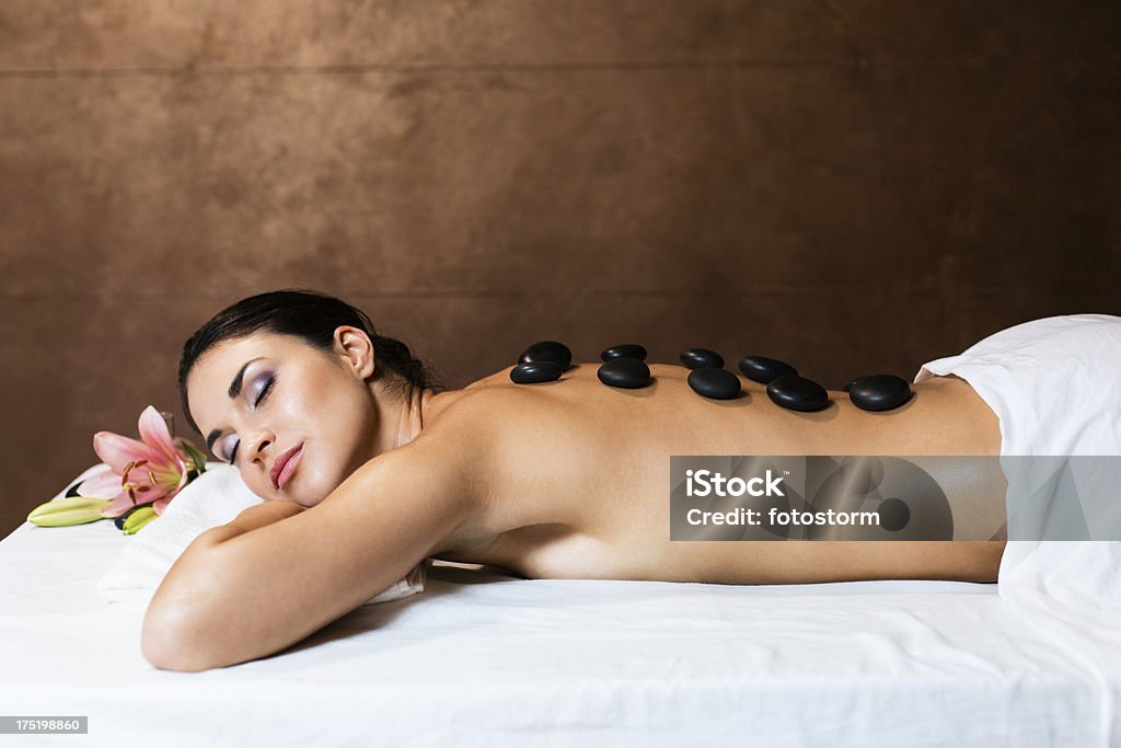 Warm stones massage Beautiful young woman having a back massage with warm stones. Lastone Therapy Stock Photo