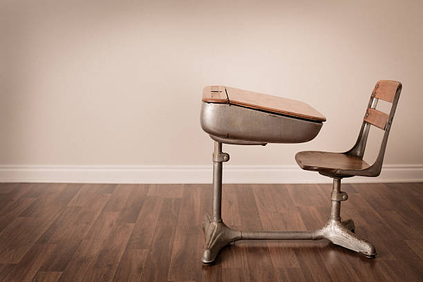 Color image of the side view of an old school desk sitting on a hardwood floor. Includes room for your text.