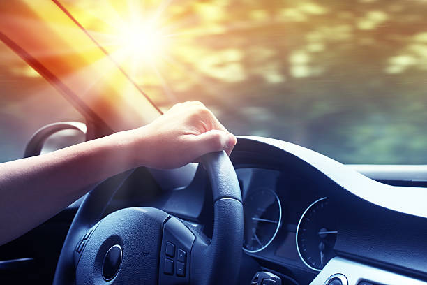 Hand on steering wheel of a car at sunset