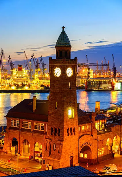 The clock tower of the landmark Hamburg St. Pauli Piers (aka Landing Stages (german: Landungsbrücke)), the ElbeRiver and Hamburg Harbour at dusk.