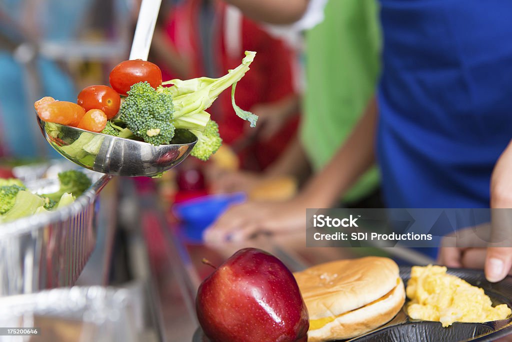 École étudiants recevoir des légumes dans la ligne du déjeuner - Photo de Cantine scolaire libre de droits