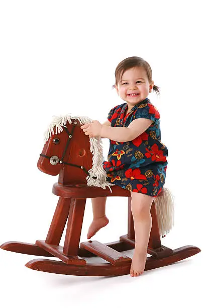 Happy little girl playing on a rocking horse.