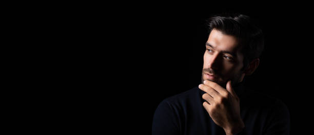 istock Planning thinking handsome young beared man portrait Attractive bearded confident guy planning and looking at copy space Smart man thinking in the dark room Cool man get good idea imagination 1752018935