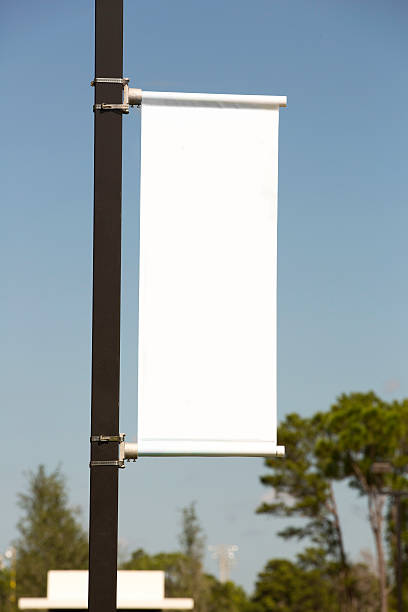 white vertical banner against a blue sky - pole 個照片及圖片檔