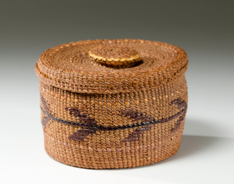 Antique Native American woven basket on a gradient background.