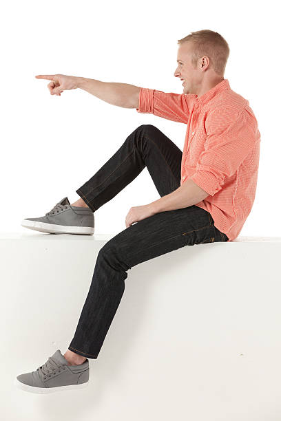 istock Man sitting on the ledge of a wall and pointing 175202909
